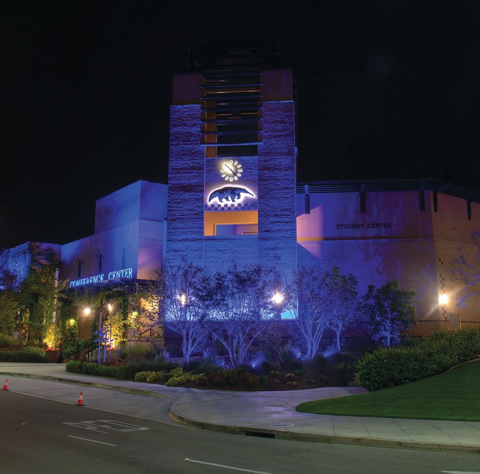 student center lit up at night with anteater sculpture and clock showing in a corner tower